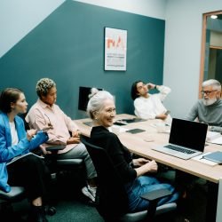 A diverse group of colleagues engaged in a meeting at a modern office, fostering teamwork and communication.