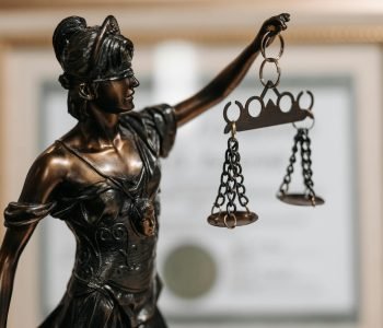 Close-up of a bronze Lady Justice statue holding scales in an office environment.