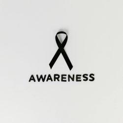 Minimalist image of a black ribbon symbolizing cancer awareness with text.